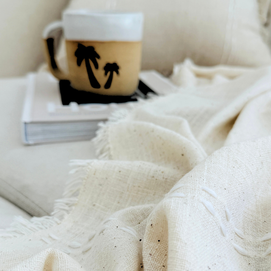 Cozy scene with a mug and book under a soft blanket.