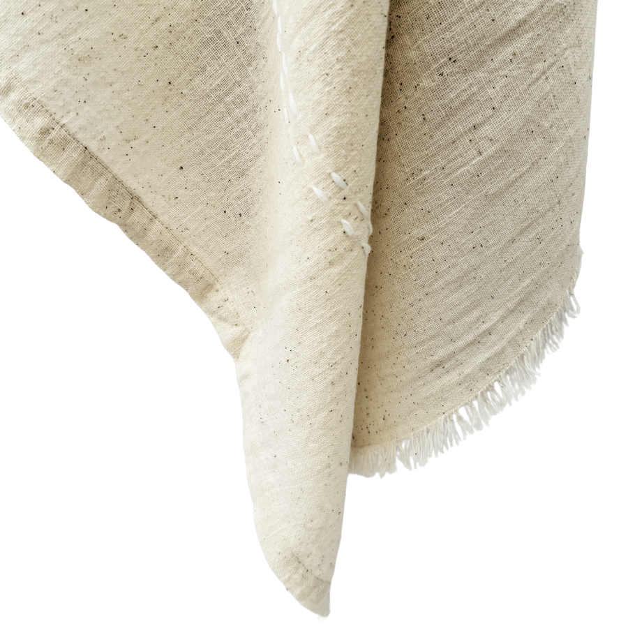 Beige woven blanket with frayed edges.