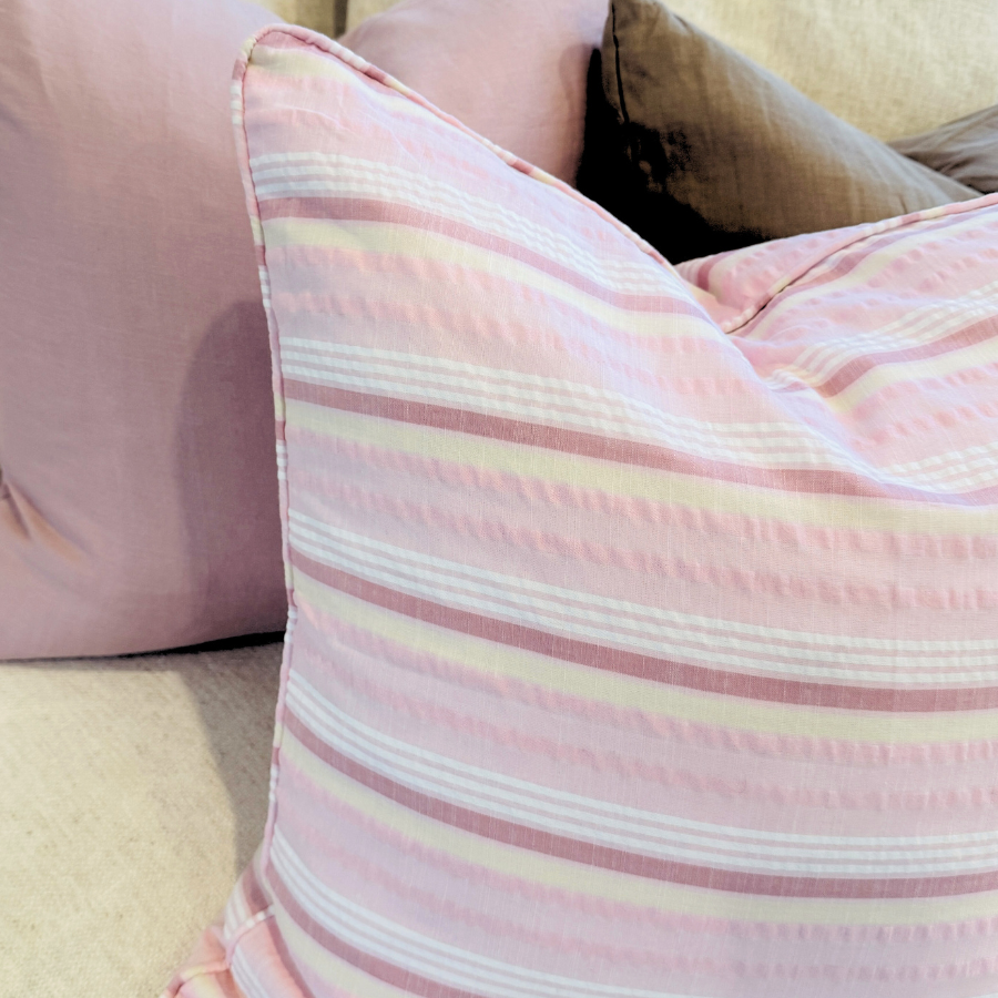 Striped pink and white cushion on a beige sofa.