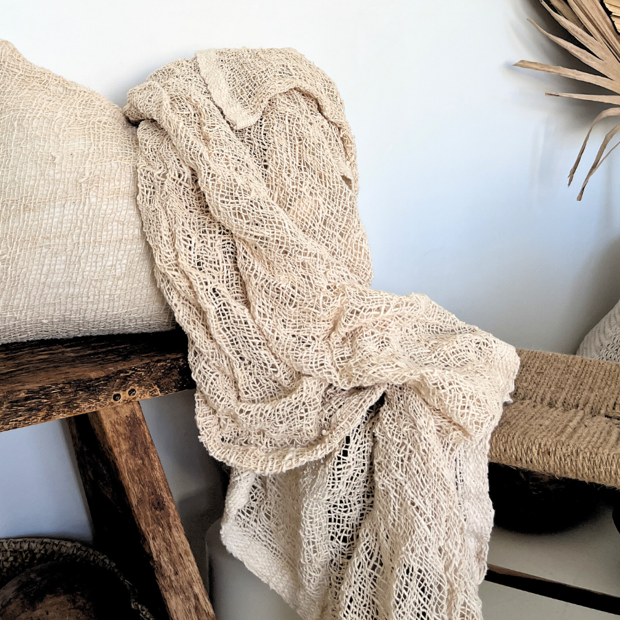 Beige textured fabric draped over a wooden surface with a white background.