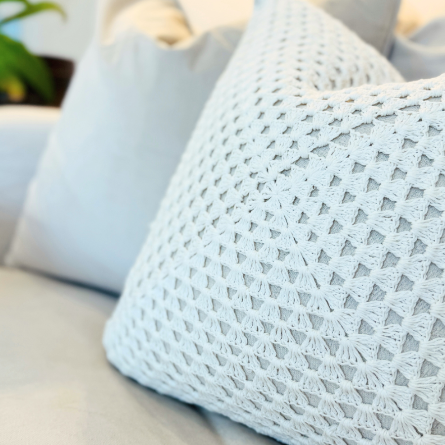 Light blue textured cushion on a beige sofa with a blurred indoor background.