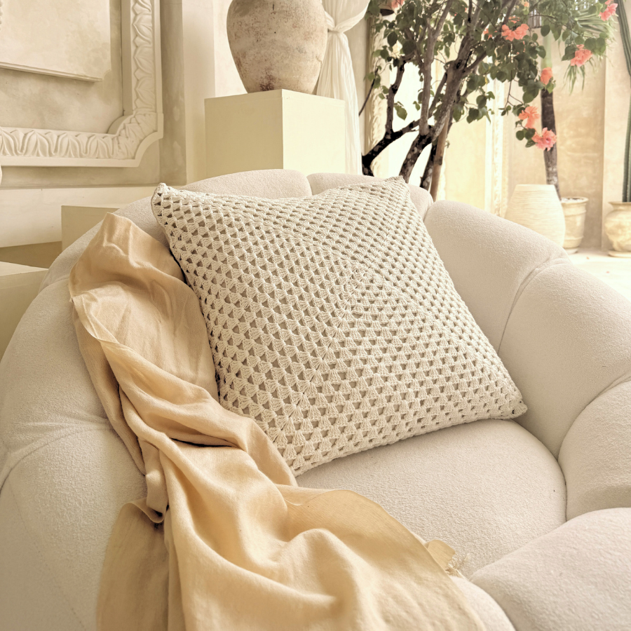 Beige sofa with a textured cushion and beige blanket, decorated with a decorative vase and floral elements.
