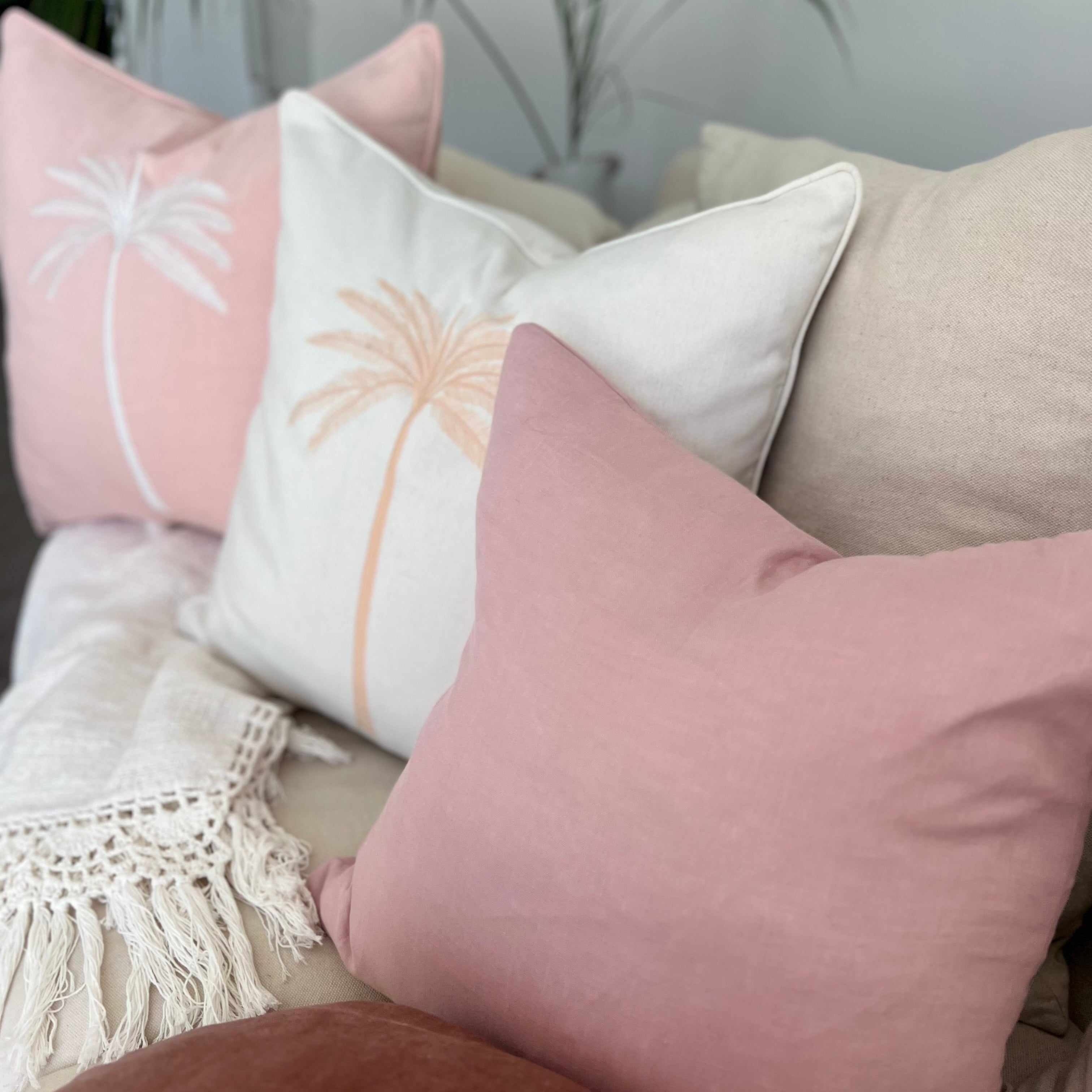 Pink cushions with palm tree decor.