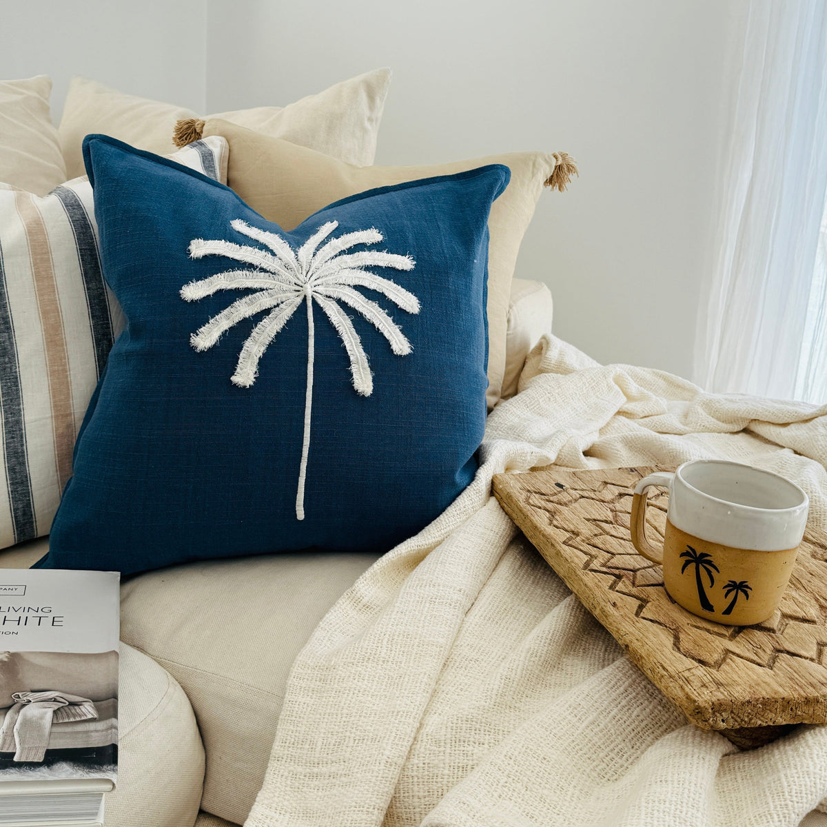 Nautical-themed cushion with palm tree design on a cozy living room sofa.
