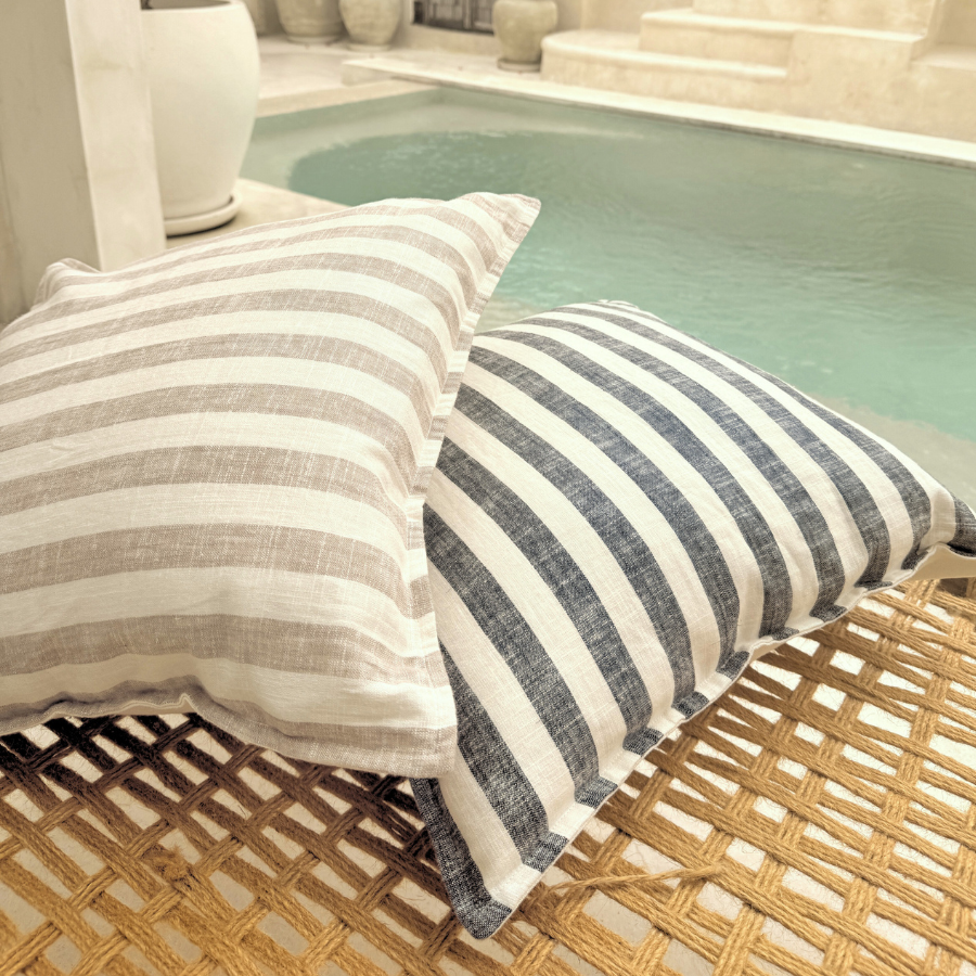 Striped cushions on a wicker chair by a poolside with decorative elements.