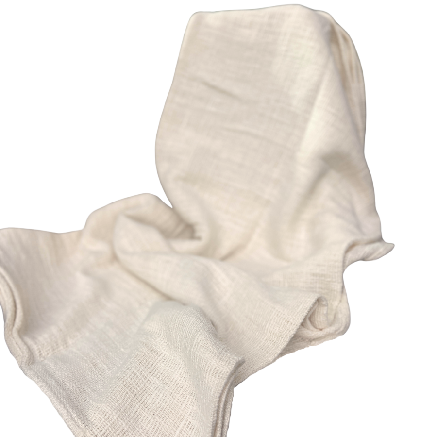 A beige cotton throw draped over a plain background, showcasing its soft texture and solid color.