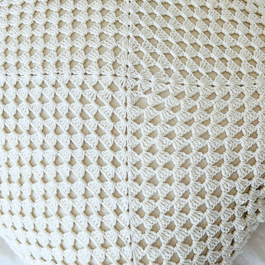 Close-up of a white crocheted blanket with a diamond pattern.