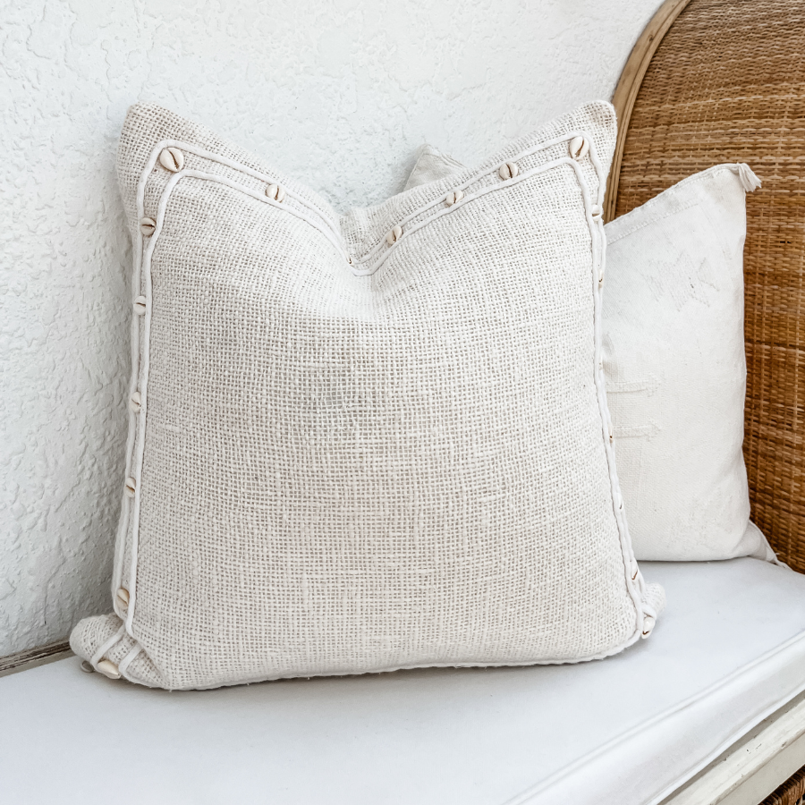 Shell decor cushion on a rattan bench.