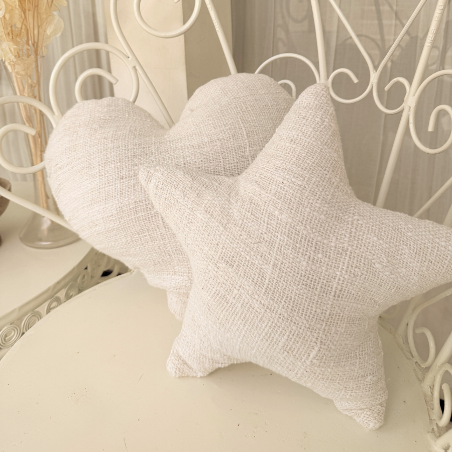 Three white textured cushion on a decorative metal bench with a neutral background.