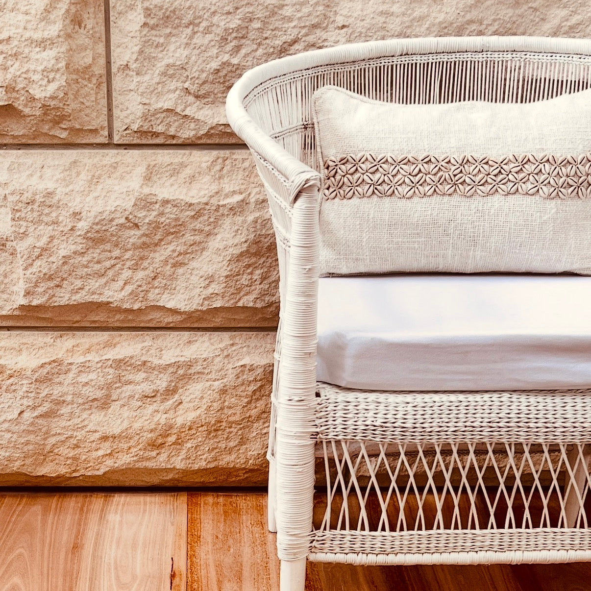 Wicker chair with cushions against a stone wall