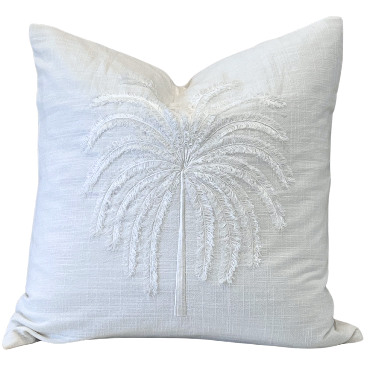 A large square throw cushion with a hand-crafted creamy ivory linen cover featuring a tufted palm tree design in the center.