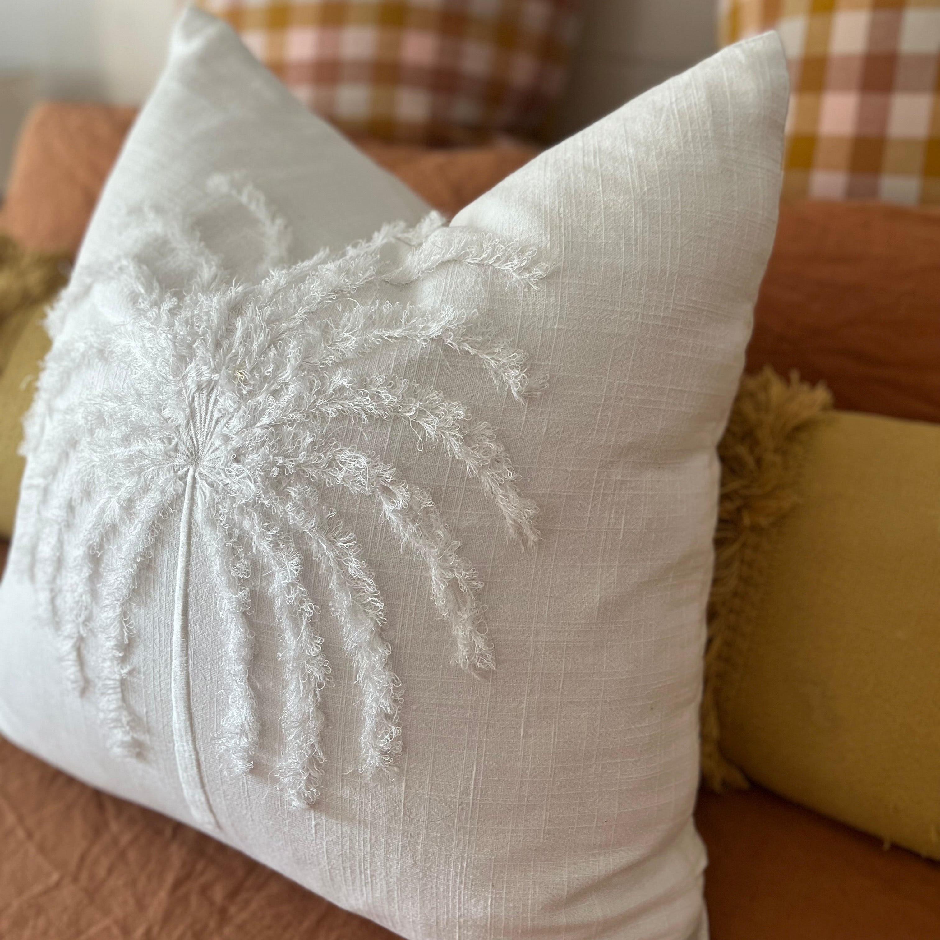 White cushion with palm tree design.