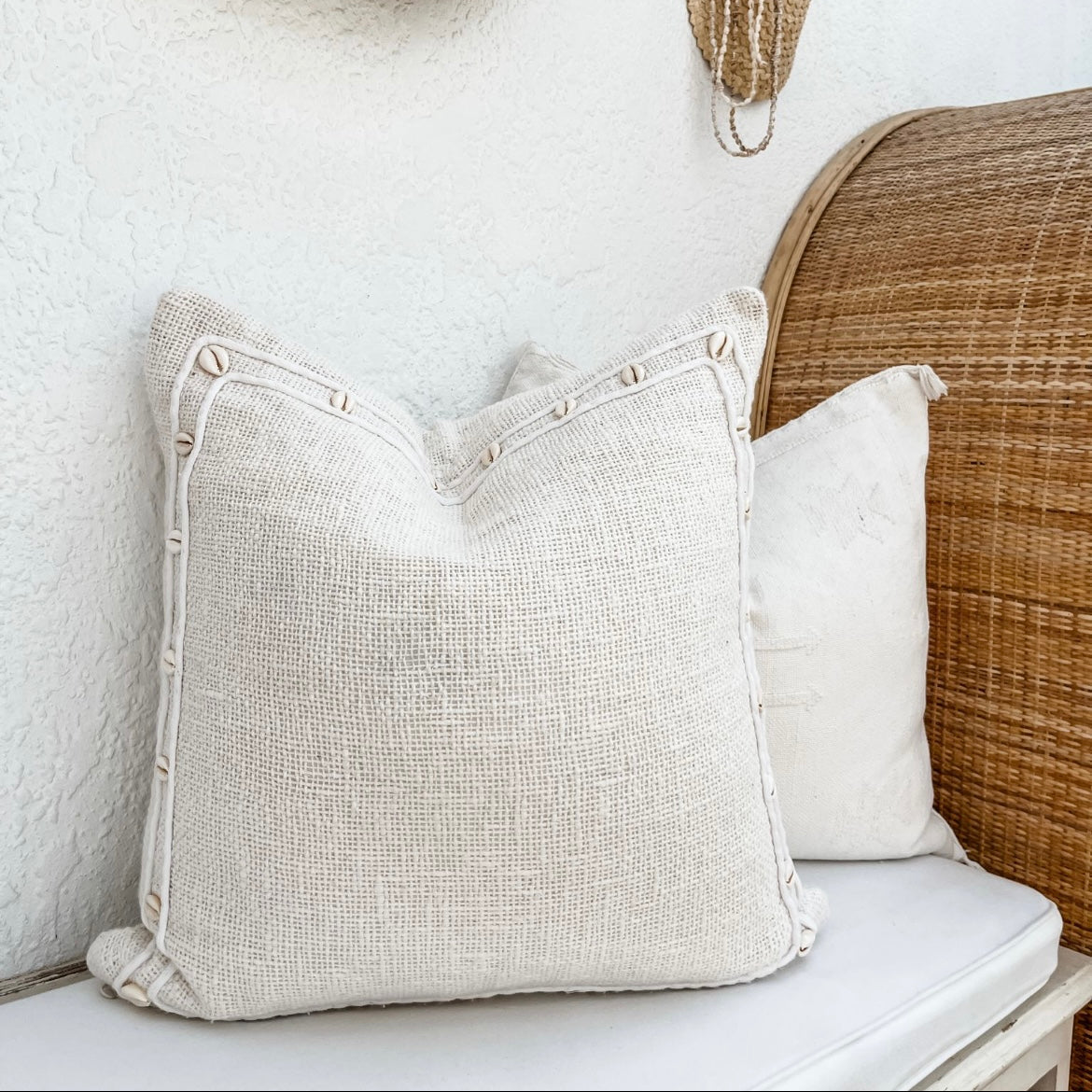 White decorative cushion with ratan decor.