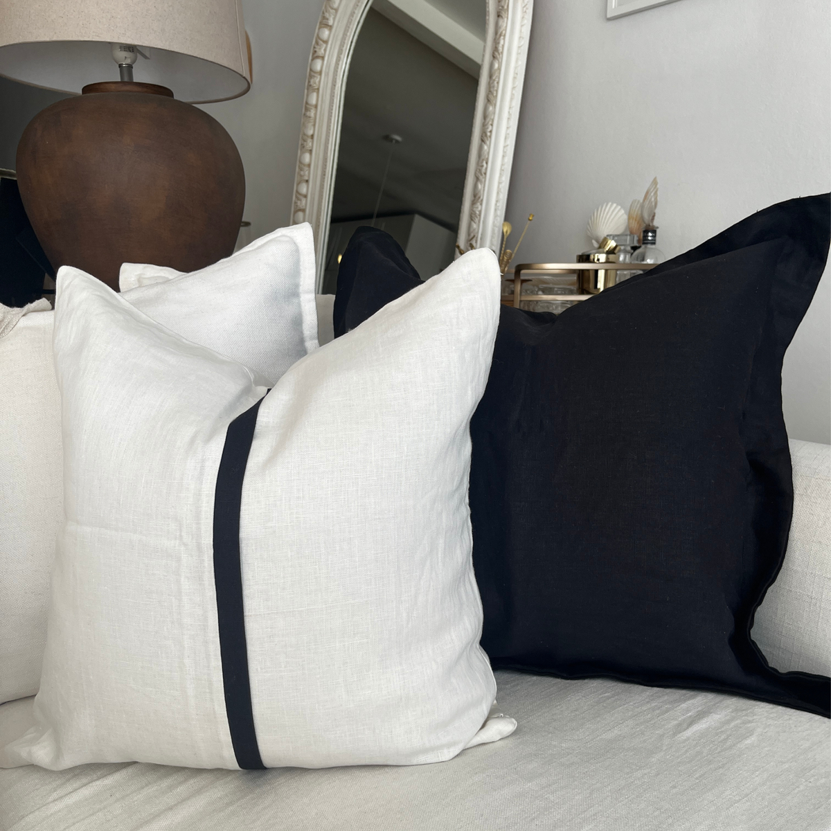 Square ivory and black stripe linen throw pillow styled on a white sofa.