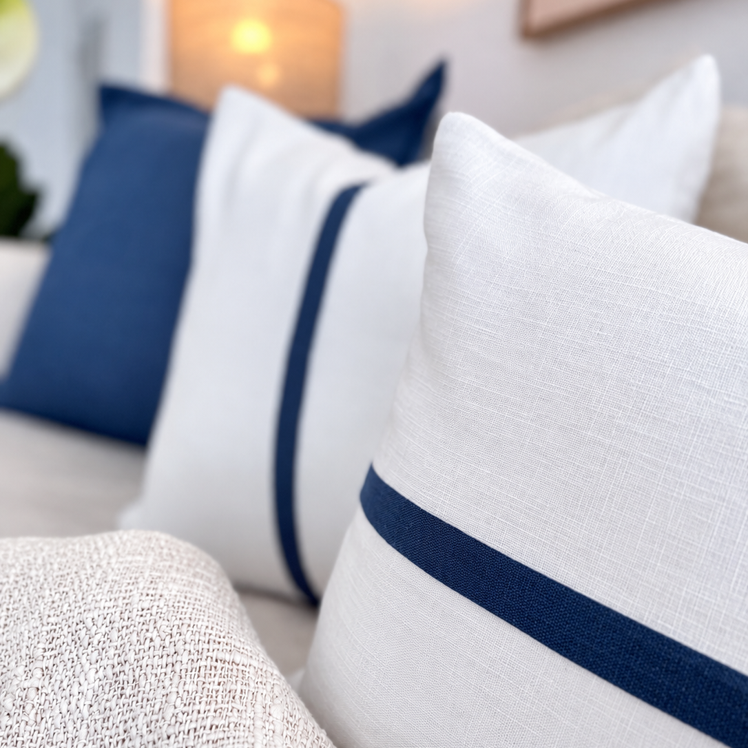 White textured throw pillows with a navy blue stripe detail, styled on a sofa.
