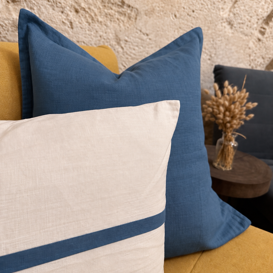 Close-up of blue and ivory linen cushions styled on a mustard sofa.