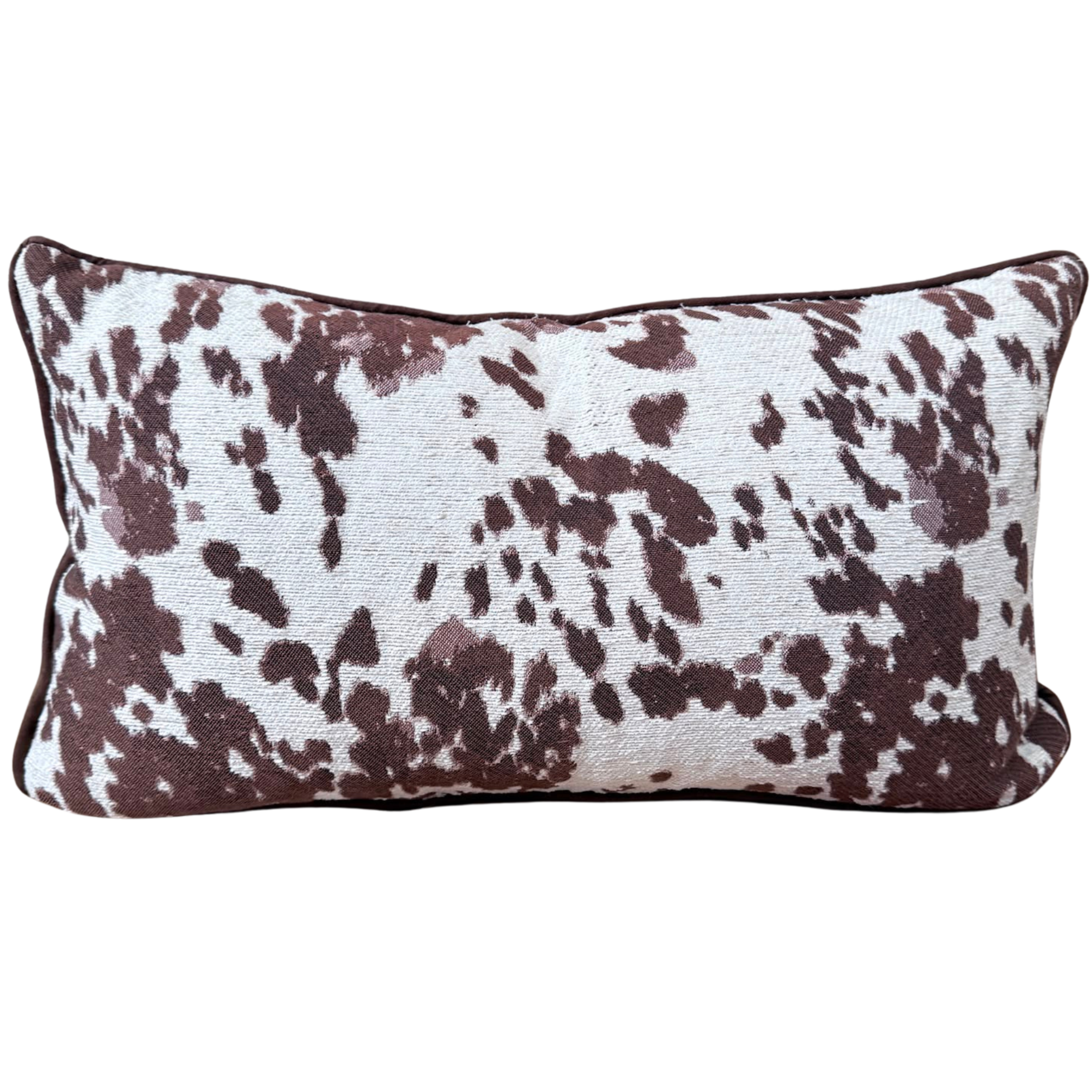 A rectangular lumbar throw cushion featuring a brown and white cow print pattern, shown against a plain white background.
