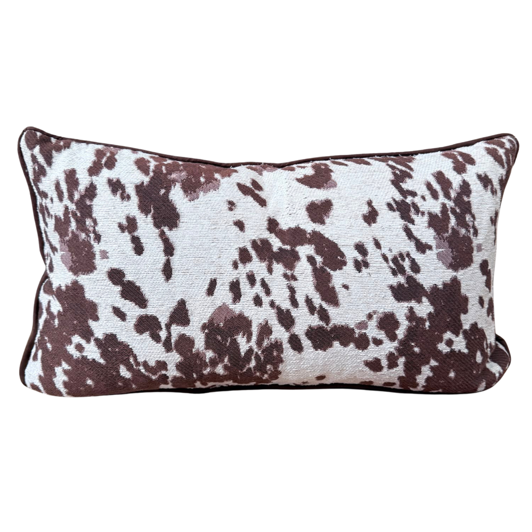 A rectangular lumbar throw cushion featuring a brown and white cow print pattern, shown against a plain white background.