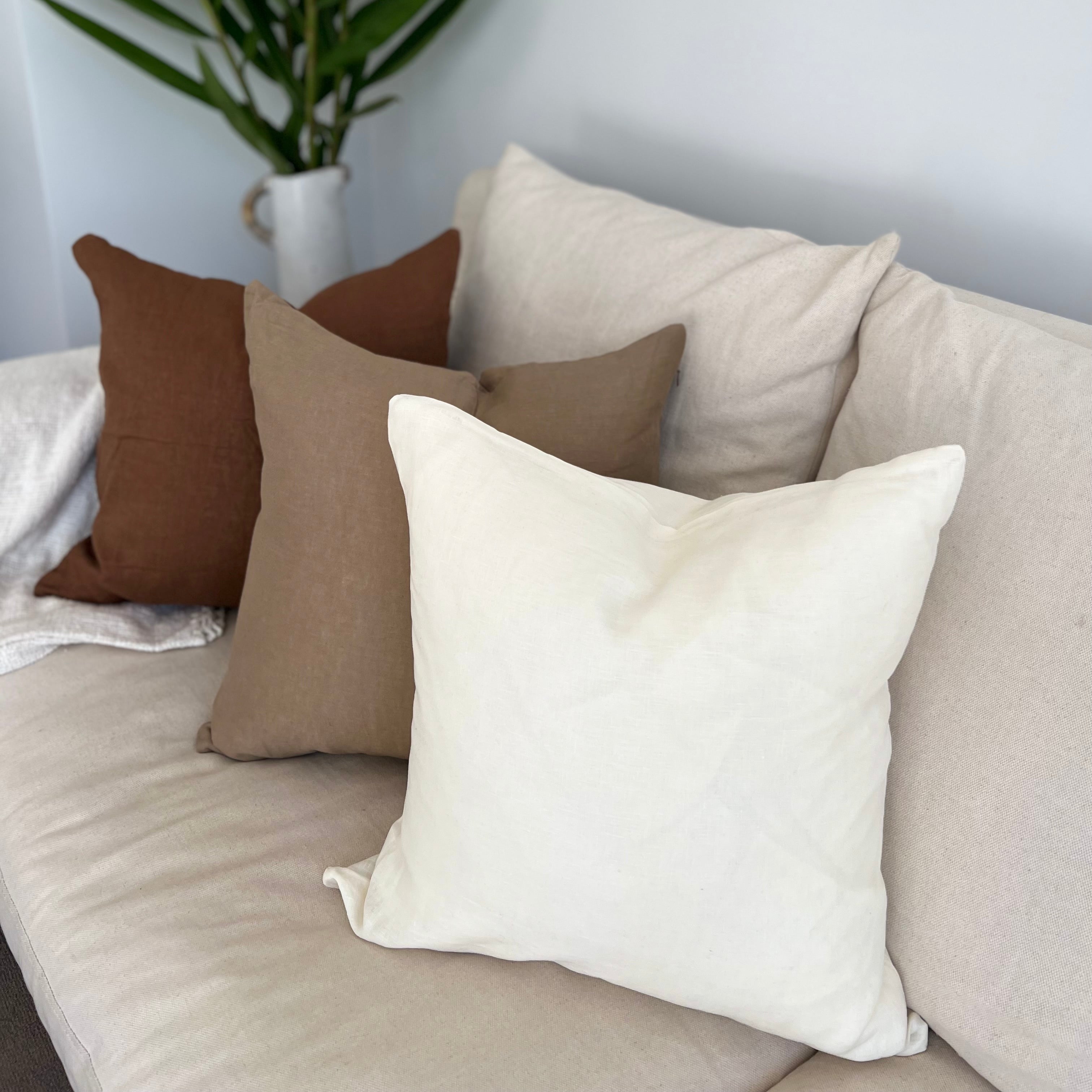 Cushions on a sofa with plant decor.