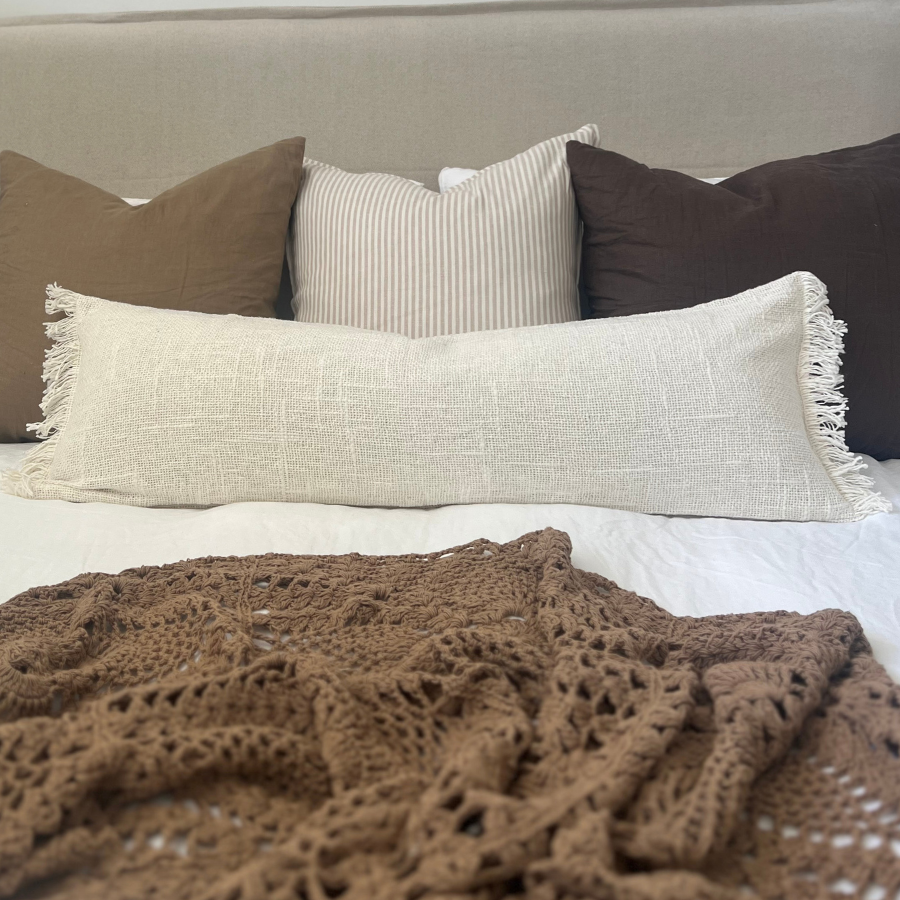 Cushions with blanket on a bed.