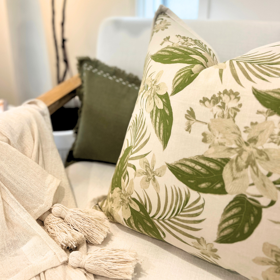 Decorative cushion on a sofa with plant on the background. 