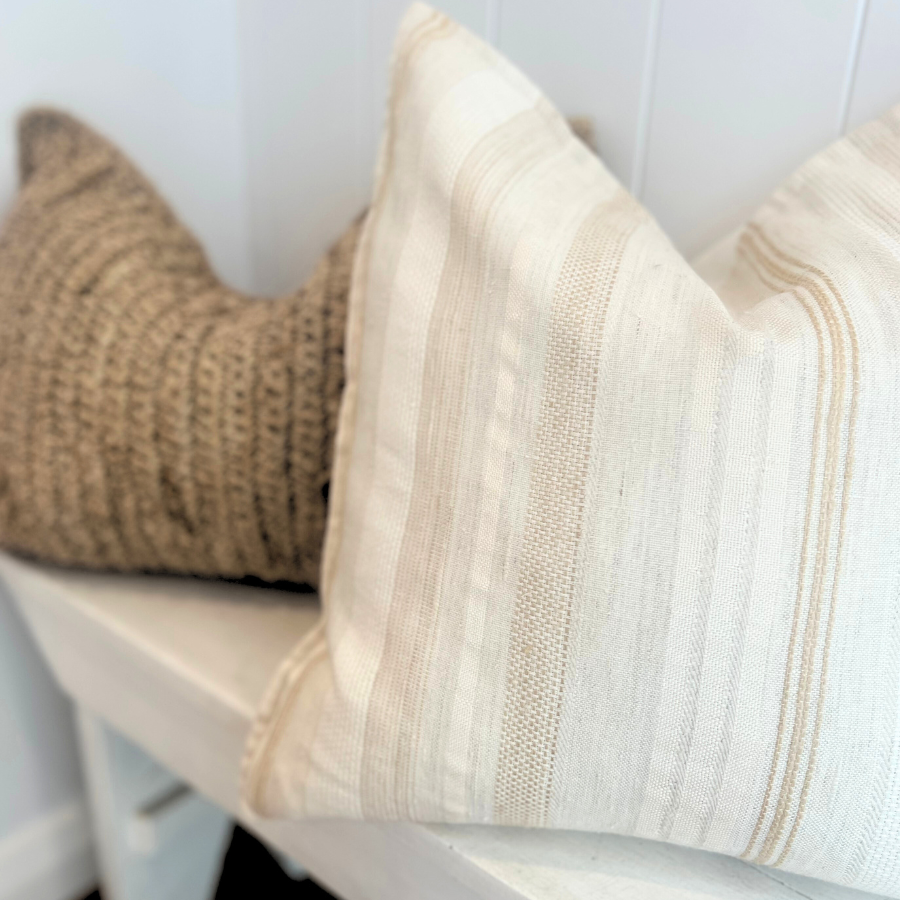 Woven cushion and white cushion on a bench.