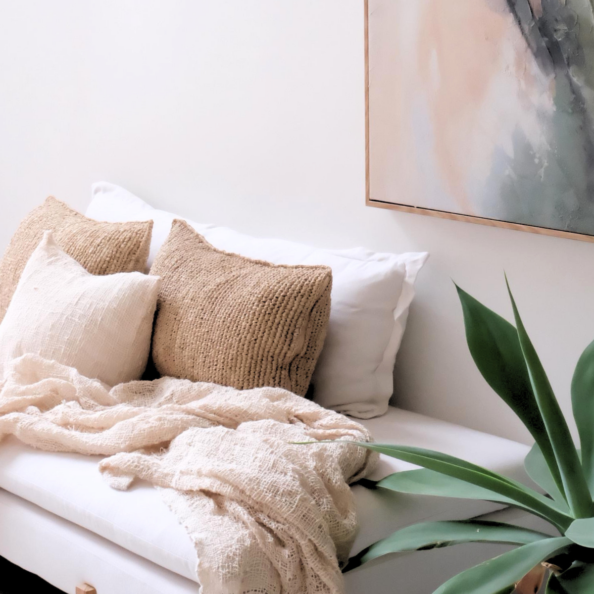 Cozy living room with a white sofa, beige throw blanket, and decorative cushion.