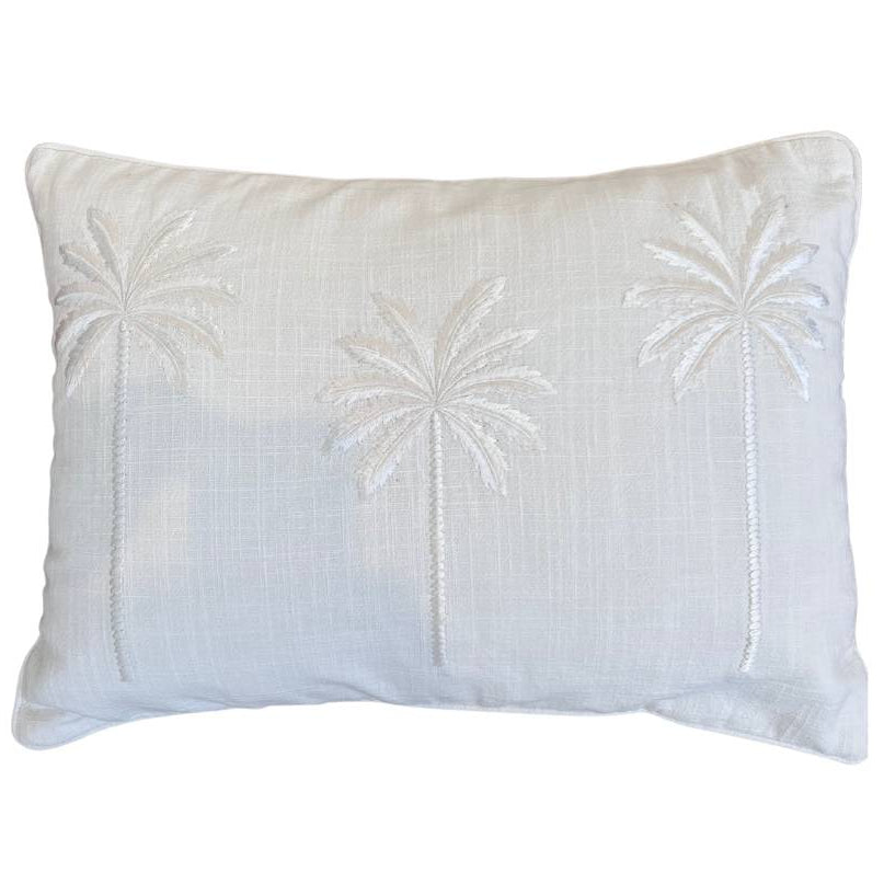 A rectangular throw cushion with three embroidered palm trees in a vertical alignment, crafted from linen with piped edges, in ivory color.